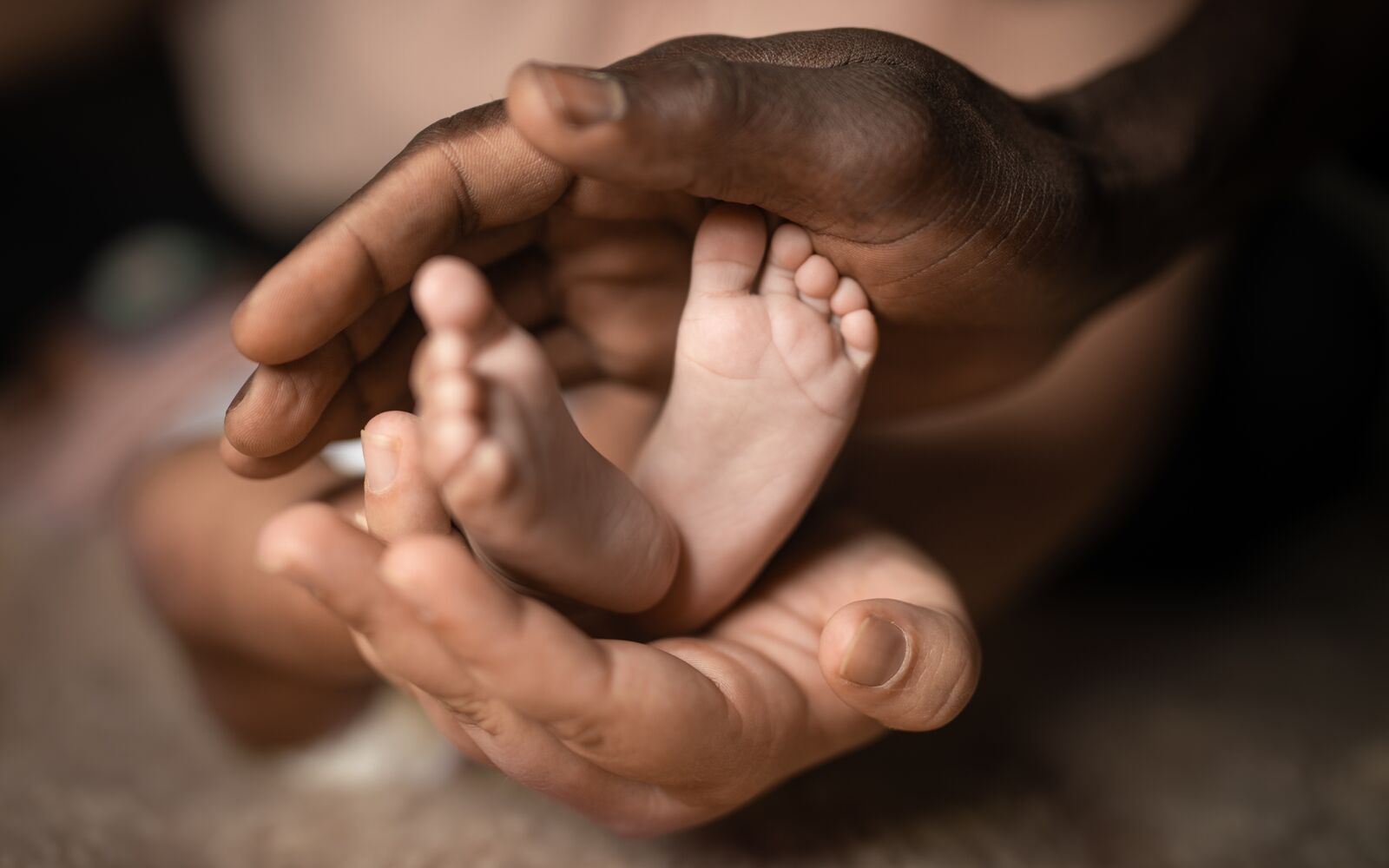 interracial family holding baby feet in hands mixed by black and white skin color